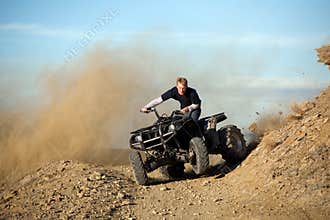 Teen riding quad ATV in hills