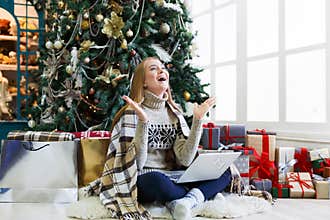 Surprised woman online on laptop at christmas interior