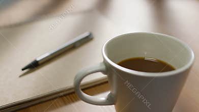 A notebook a pen and a cup of coffee