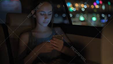 Young adult female in taxi using smart phone.