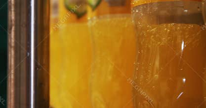 Close up bottles being filled with juice on production line