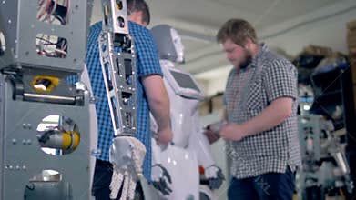 Technicians assembling several robots in a workshop.