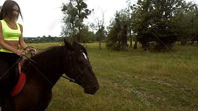 Young cute girl rides on horseback in a circle
