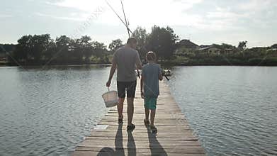 Father and son going fishing with rods on lake