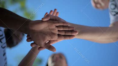 Low angle of positive volunteers holding hands together
