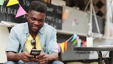 African american man with smartphone at food truck