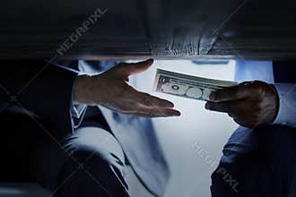 Hands passing money under table corruption bribery