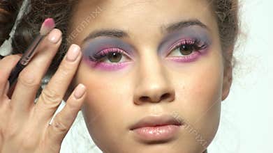 Hand of visagist applying eyeshadow.