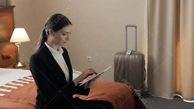 Business, technology, internet and hotel concept - happy young businesswoman with tablet pc computer lying in hotel in