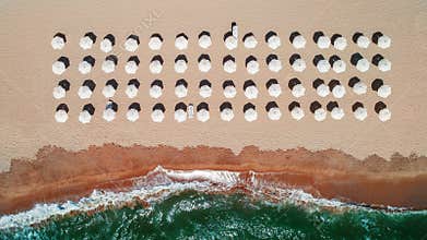 Aerial top view on the beach. Umbrellas, sand and sea waves