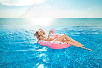 Summer Vacation. Woman in bikini on the inflatable donut mattress in the SPA swimming pool.