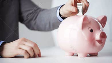 Close up of man putting money into piggy bank