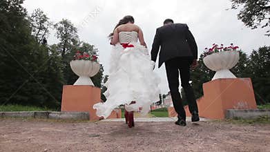 Newly married couple walk on park holding hands