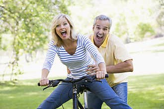 Couple on bike outdoors smiling and acting scared