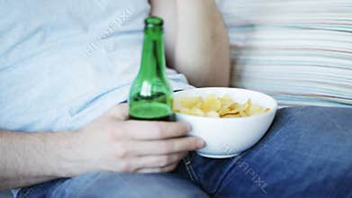 Close up of man eating chips and drinking beer