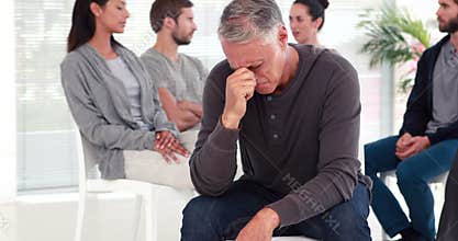 Man comforting another in rehab group at therapy