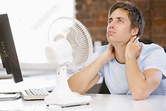 Businessman in office with computer and fan