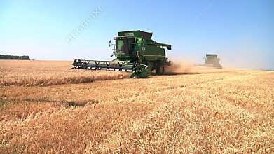 Modern John Deere combine harvesting grain on a storage trailer