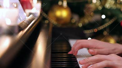 Girl playing piano near Christmas tree