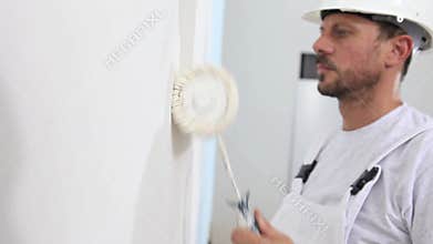 Painter man at work, with roller painting wall, painter house