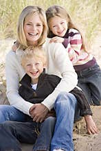 Mother and two young children sitting on beach