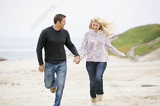 Couple running at beach holding hands