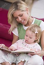 Mother in living room reading book with baby
