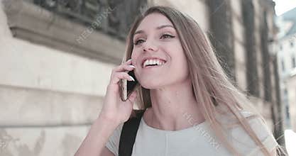 Happy woman walking and talking via mobile phone