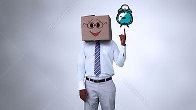 Businessman with a carton on the head pointing at an animated alarm clock