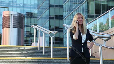 Young woman standing on the stairs and talking on a cellular phone