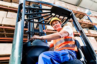 Forklift driver in industrial logistics warehouse