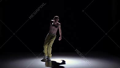 Breakdance dancer in yellow suit goes on dance on black, shadow, slow motion