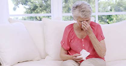 Senior woman crying on the sofa