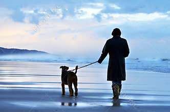 Woman walking her dog at sunset on deserted Australian beach