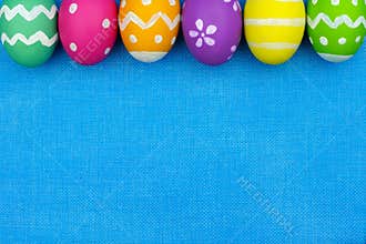 Easter egg top border over blue burlap background