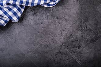 Top view of checkered kitchen tablecloth on granite - concrete - stone background. Free space for your text or products