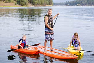 Attractive family kayaking and paddle boarding together on a beautiful lake