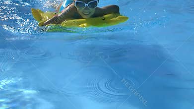 Child wearing sunglasses floating on inflatable ring are swimming in pool.