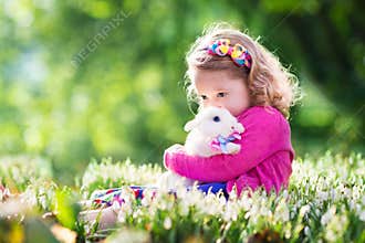 Little girl playing with bunny on Easter egg hunt