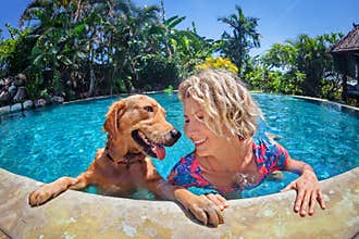 Funny portrait of smiley woman with dog in swimming pool