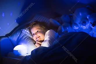 Little girl reading a book in bed