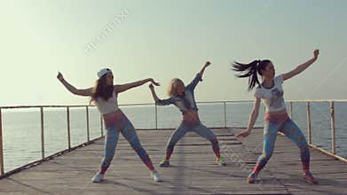 Booty dance by girls teenager on a wooden berth at the sea