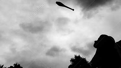 Unrecognized silhouette person Juggling 5 clubs in the air