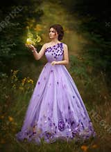 Beautiful girl in a gorgeous purple long dress, holding a candle