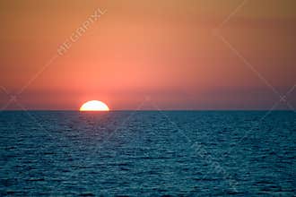 Sun setting behind sea horizon