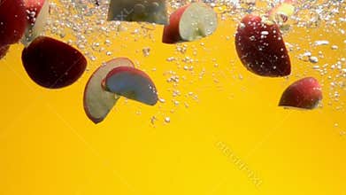 Sliced red apples falling into water