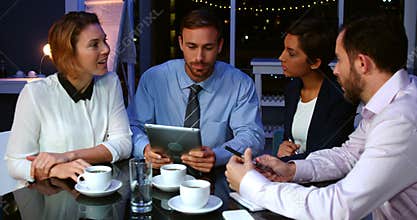 Businesspeople discussing over digital tablet in office