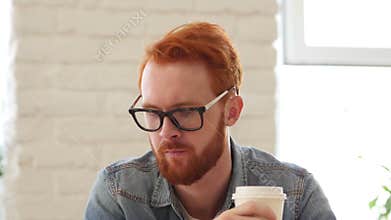 Man with Beard and Red Hairs Drinking Coffee, Tea in Office, Portrait