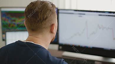 The programmer works at office behind 3 monitors