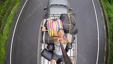 Man selfie on the roof of car was running on the road.